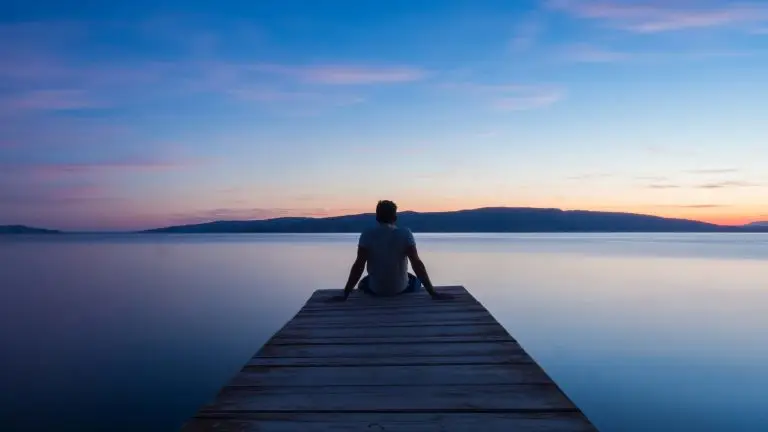 mindfulness example of a man sitting on a jetty watching the sunset in a mindful way