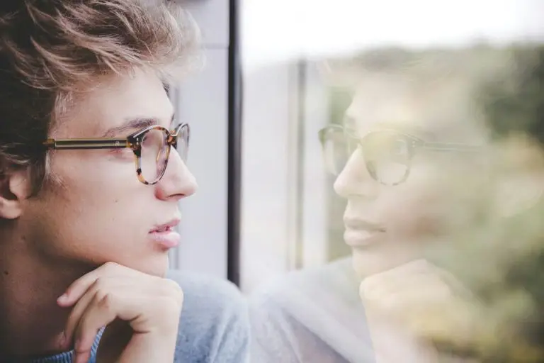 young man thinking, with his reflection in a window