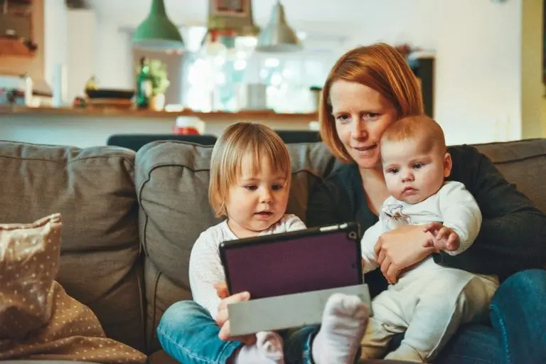 woman sitting on a sofa with 2 small children.