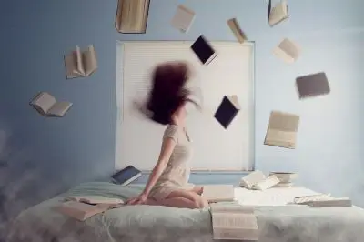 woman on bed with books flying around her head