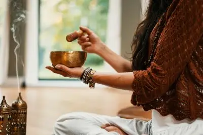 woman sitting with a Tibetan singing bowl and incense.